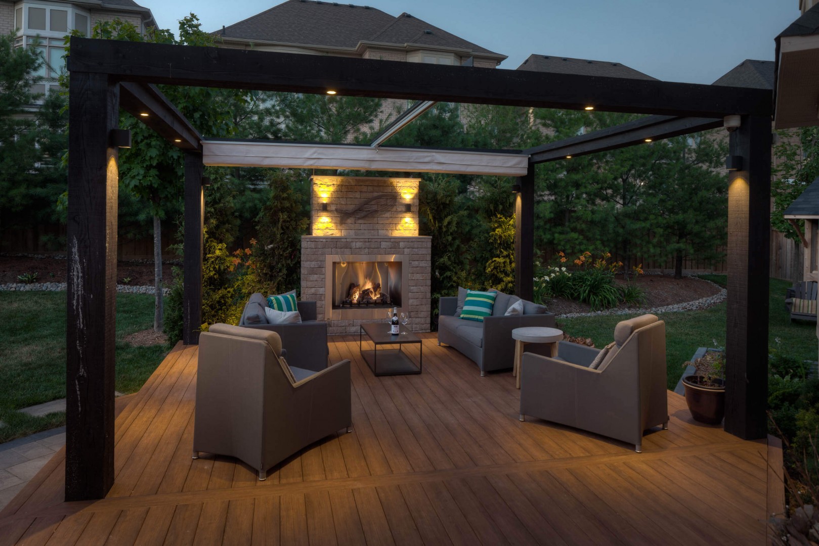 An image of an outdoor covered deck, featuring a hot tub, stainless-steel barbeque and outdoor conversation set.