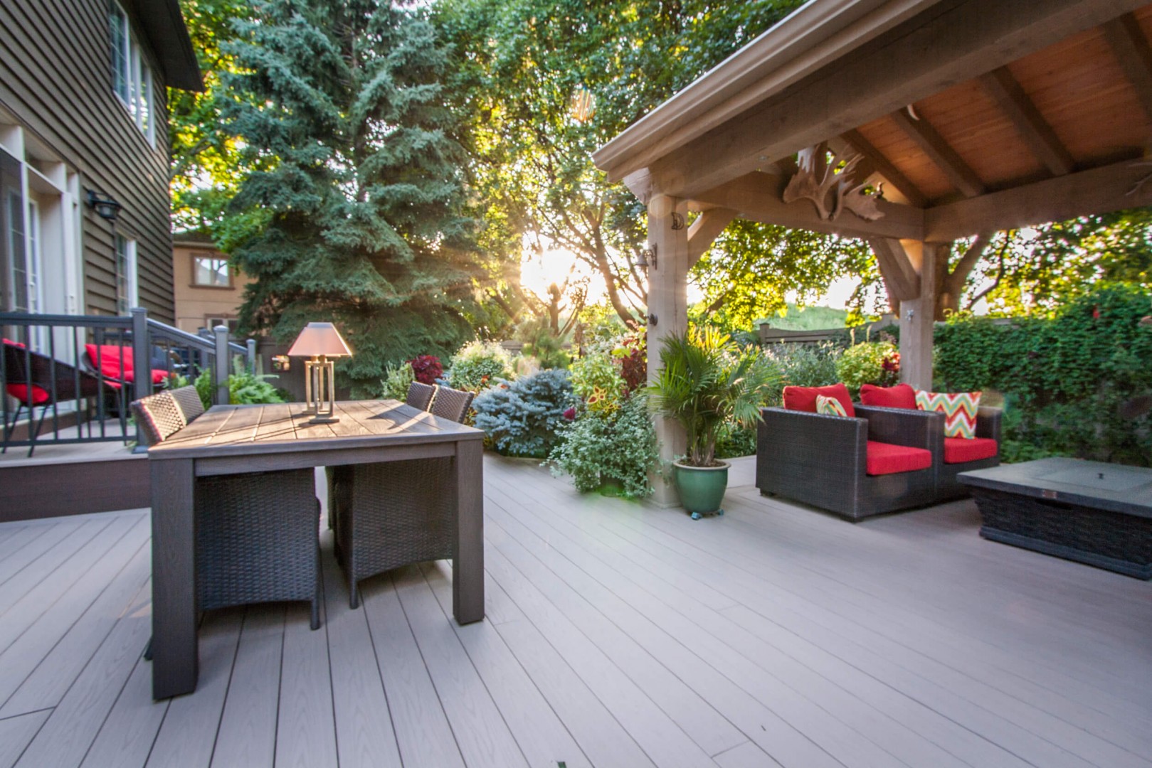 An image of an outdoor covered deck, featuring a hot tub, stainless-steel barbeque and outdoor conversation set.