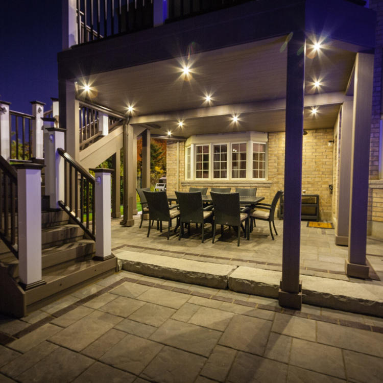 An image of an outdoor covered deck, featuring a hot tub, stainless-steel barbeque and outdoor conversation set.