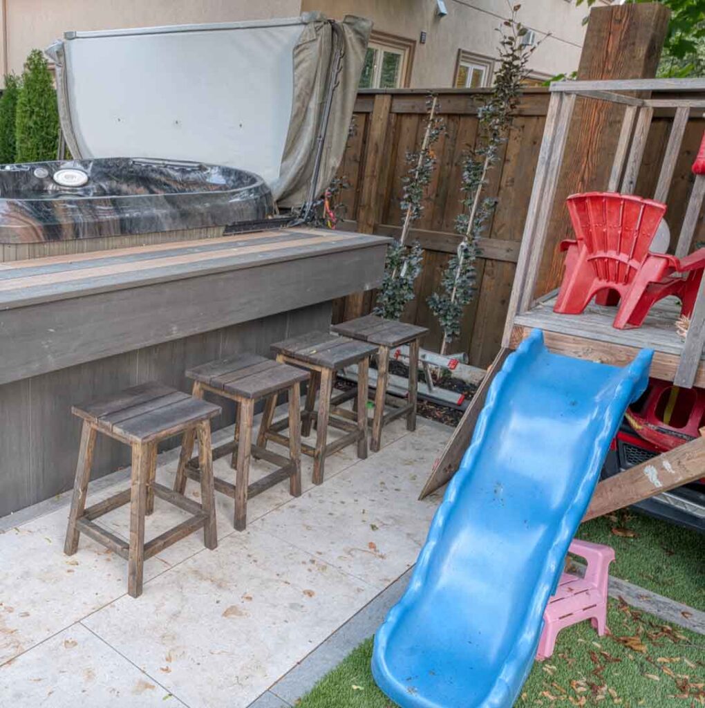 Backyard design with a hot tub for adults and a playground area for kids, creating separate spaces for everyone