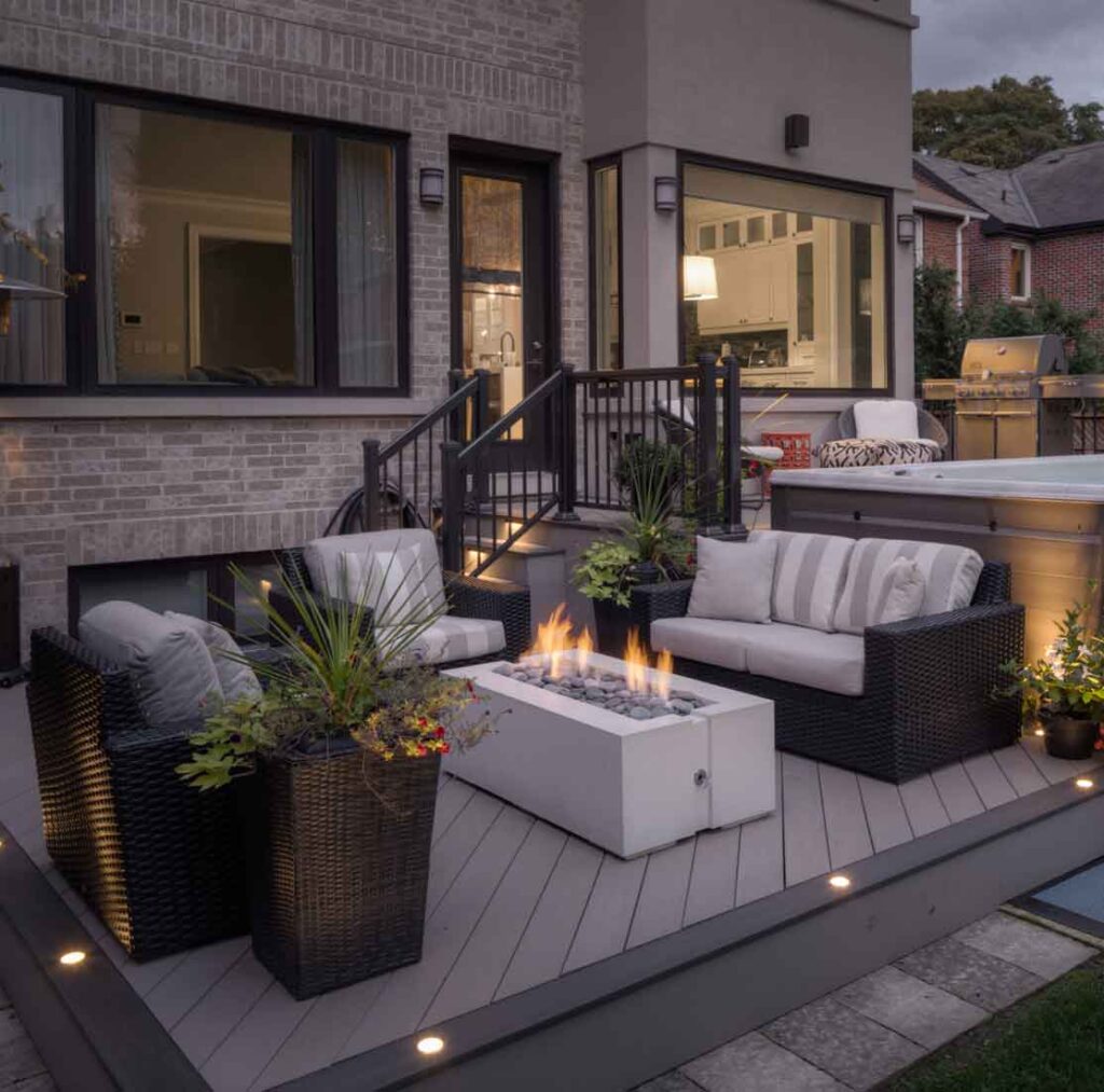 cozy composite deck with a fire pit lights and a swim spa