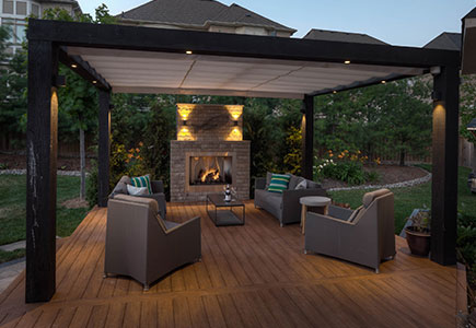Modern Brampton backyard featuring angled design, PVC deck with timber pergola, lower stone patio, BBQ island, bar area, and retractable awnings.