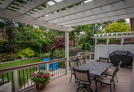 Traditional-style Toronto backyard with PVC decking, white-painted cedar pergola, matching railings, privacy screen, and skirting.